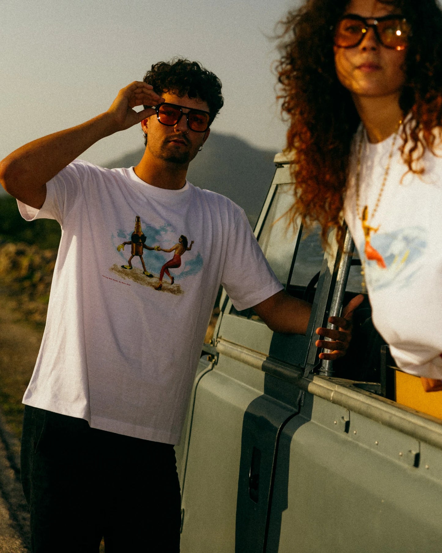 Omnia Bona ‘Dancing Beer Bottle’ Retro Graphic T-Shirt worn by two models at a casual outdoor gathering