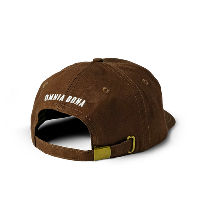 Rear view of brown Omnia Bona baseball cap featuring white embroidered logo and brass adjustable strap