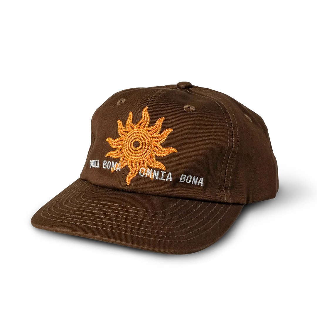 Brown baseball cap featuring embroidered orange sun design and white “OMNIA BONA” text – premium streetwear accessory
