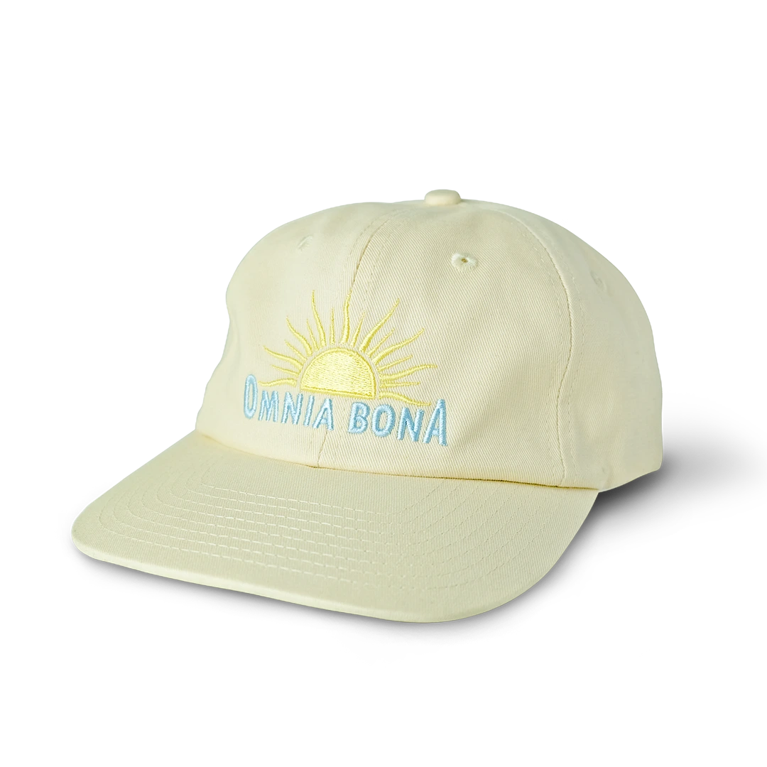 Cream-colored baseball cap with yellow sun and light blue “OMNIA BONA” embroidery – minimalist summer streetwear hat