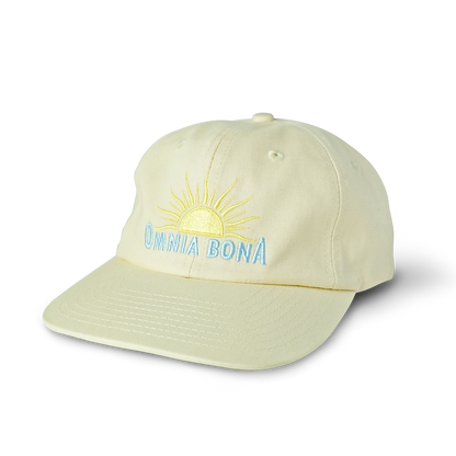 Cream-colored baseball cap with yellow sun and light blue “OMNIA BONA” embroidery – minimalist summer streetwear hat